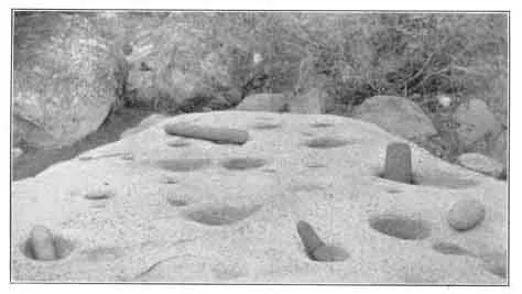 HO'-YAS AND ME-TATS'. Rude mortars and pestles for grinding acorn meal. The holes have been worn in the granite by constant use